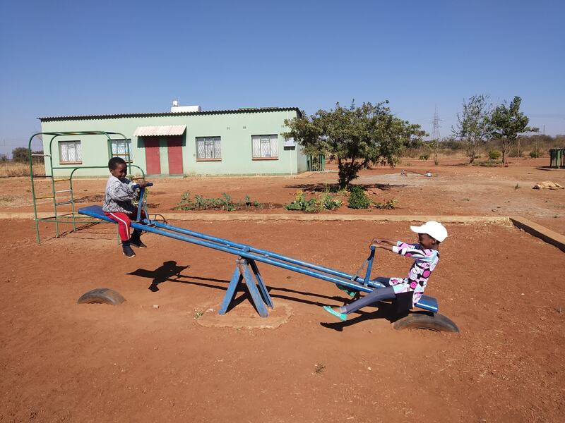 Children playing on a seesaw at S.M.I.L.E. Village