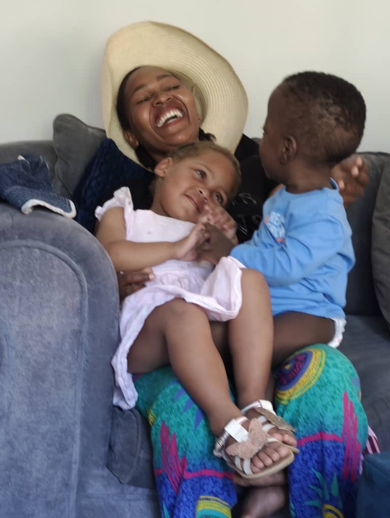 A mother laughing on the couch with her two children at S.M.I.L.E. Village